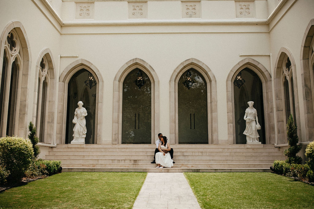 An engaged couple is photographed on the steps of Chateau Nouvelle, a chateau inspired houston tx wedding venue