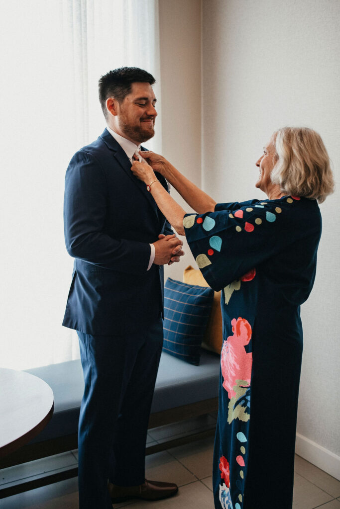 A mother assists her son with his tie as he gets ready for his texas hill country elopement