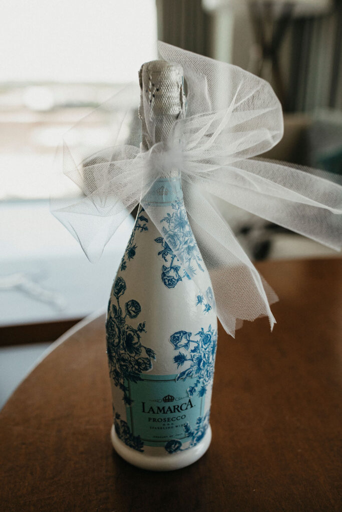 A bottle of champagne in the couples' wedding colors is photographed at their trattoria lisina wedding