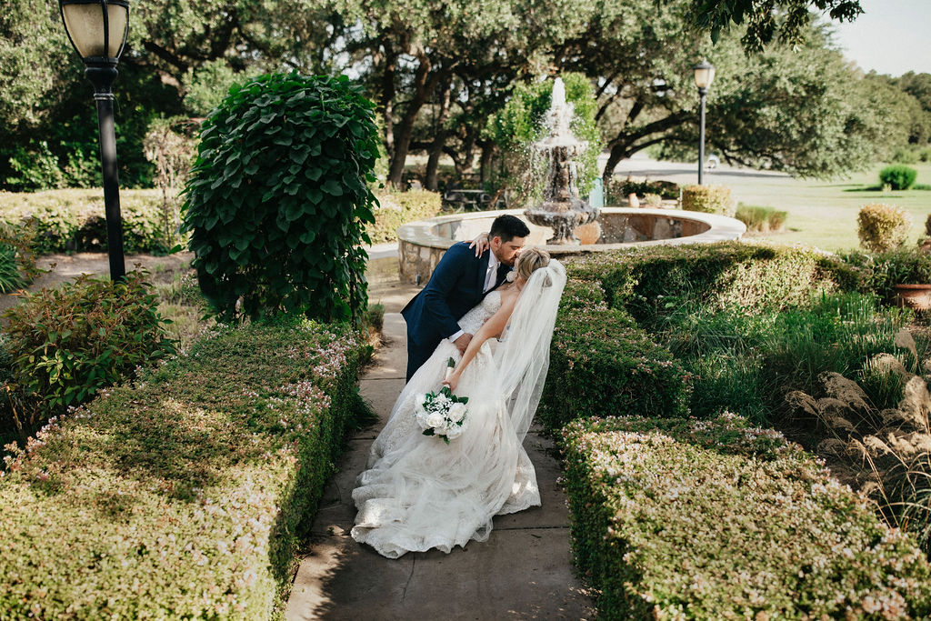 Newlyweds share a kiss next to the fountain at their trattoria lisina wedding