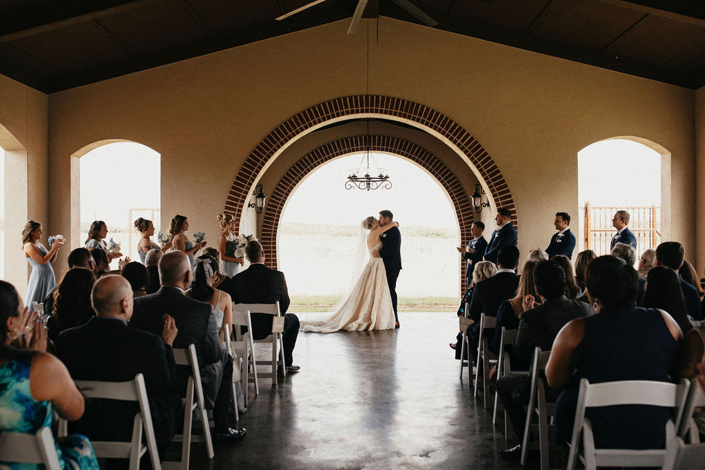 Newlyweds share a kiss under a brick arch after their vows at their trattoria lisina wedding