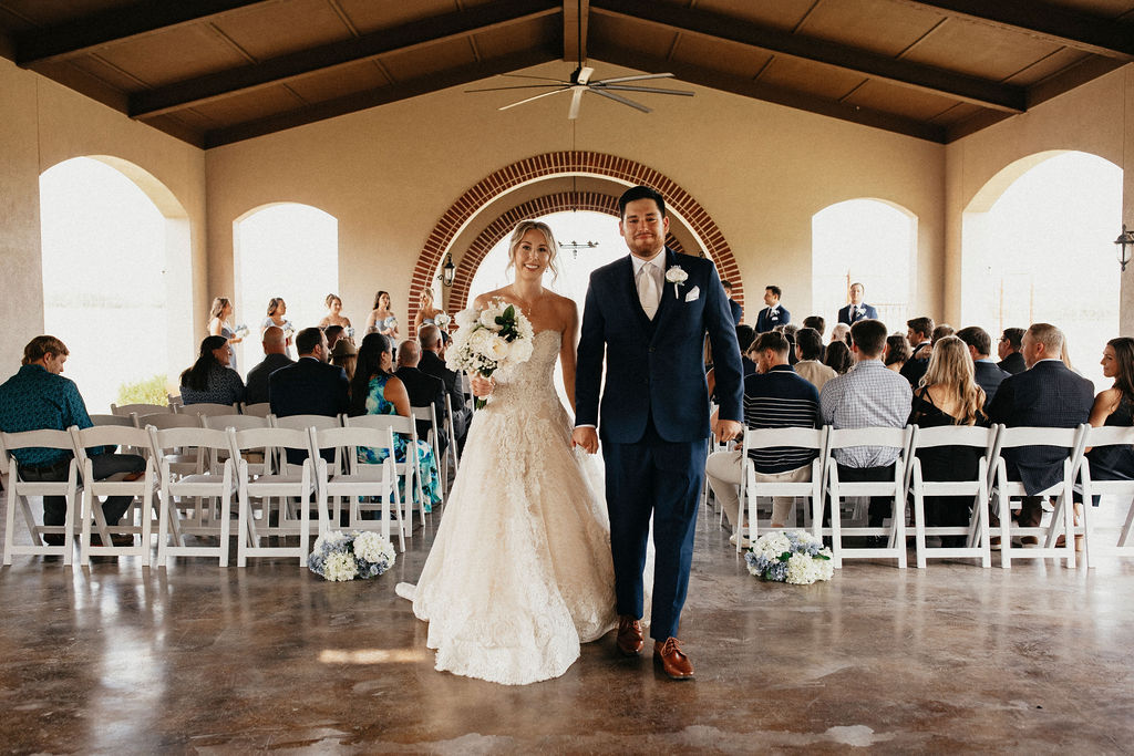 Newlyweds walk hand-in-hand down the aisle at their texas hill country elopement held at Trattoria Lisina