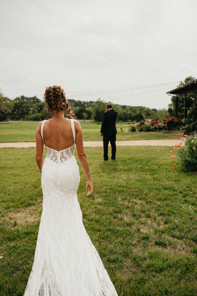A bride walks toward her father for a first look at her Austin TX wedding at Pecan Springs Ranch