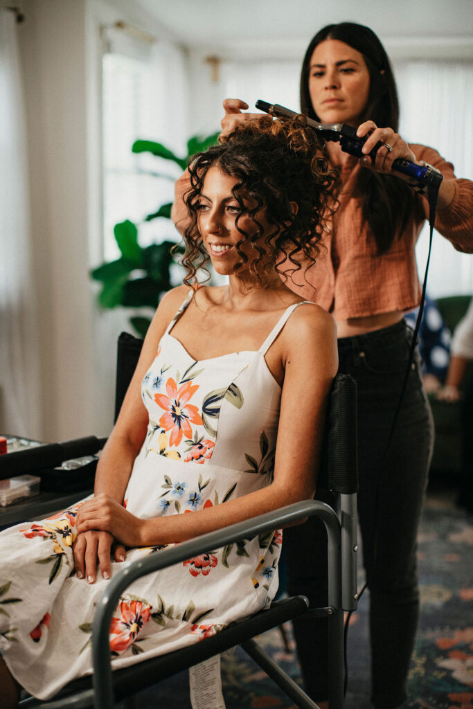 A bride has her hair curled as she gets ready for her Austin TX wedding at Pecan Springs Ranch