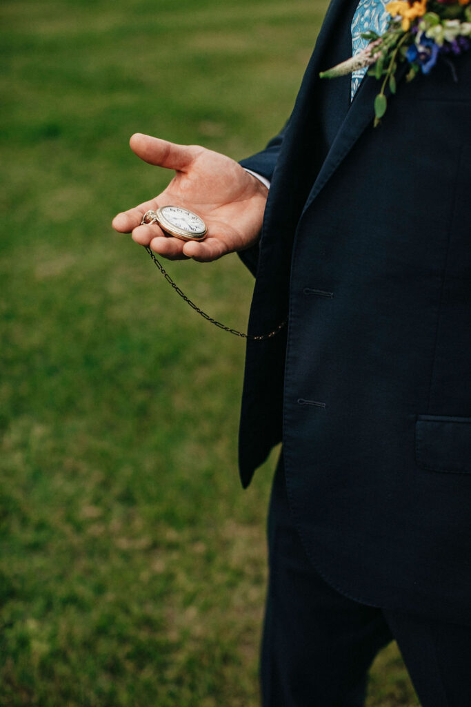 A groom looks at his pocket watch, a gift at his Pecan Springs Ranch wedding