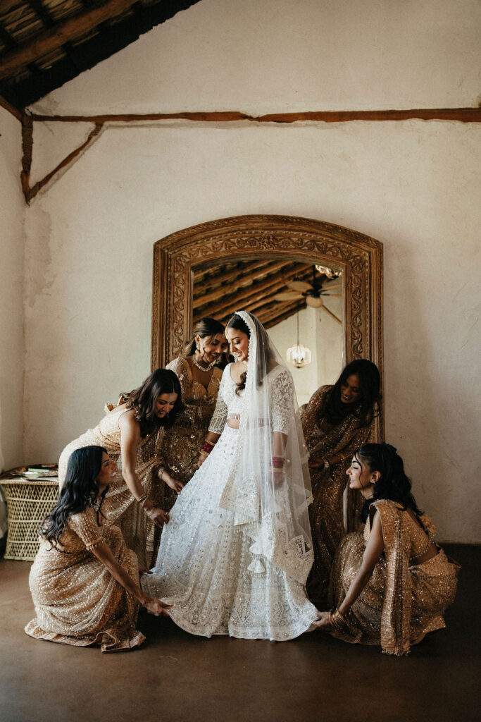 Bridesmaids help a bride with her dress at her Three Bells Mission wedding in Texas