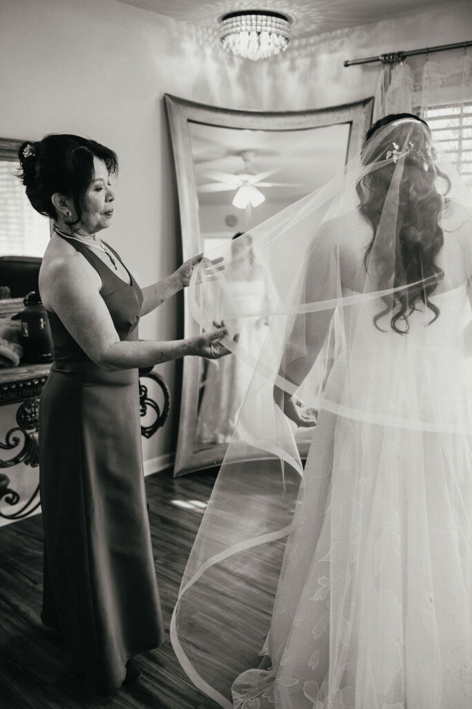 A b+w image of the mother of the bride adjusting her daugther's veil before her wedding at kindred oaks georgetown
