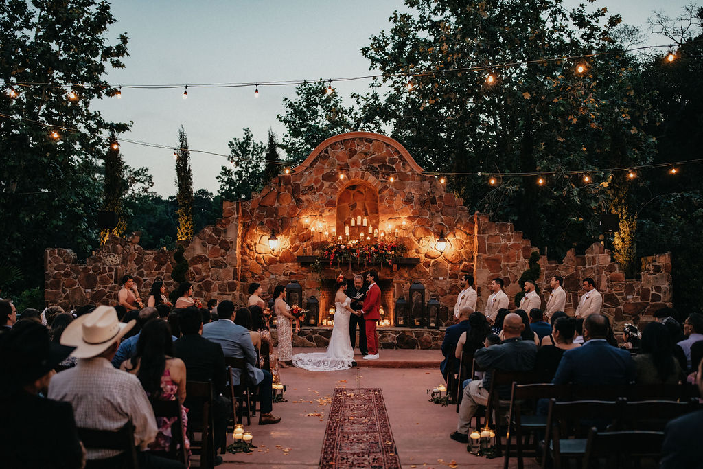 A bride and groom exchange vows at the outdoor fireplace at Madera Estates, an outdoor wedding venue in Houston 
