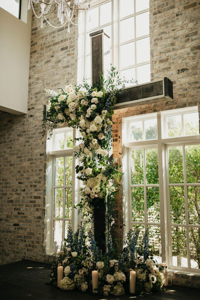 A floral covered cross is positioned at the end of the aisle at a peach orchard texas wedding 