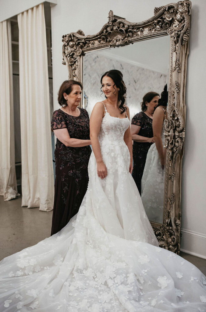 The mother of the bride assists with her wedding dress at the peach orchard venue