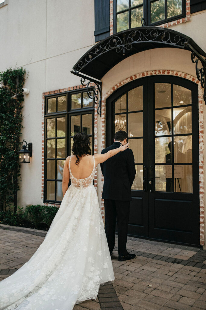 A bride taps her groom on the shoulder for a first look at their the peach orchard venue wedding 