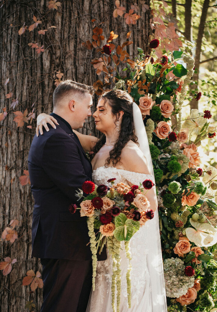 Newlyweds pose next to wedding florals at cypress valley event center