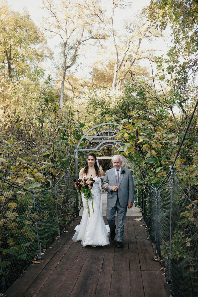 A bride walks down the aisle at her Spicewood TX treehouse wedding 