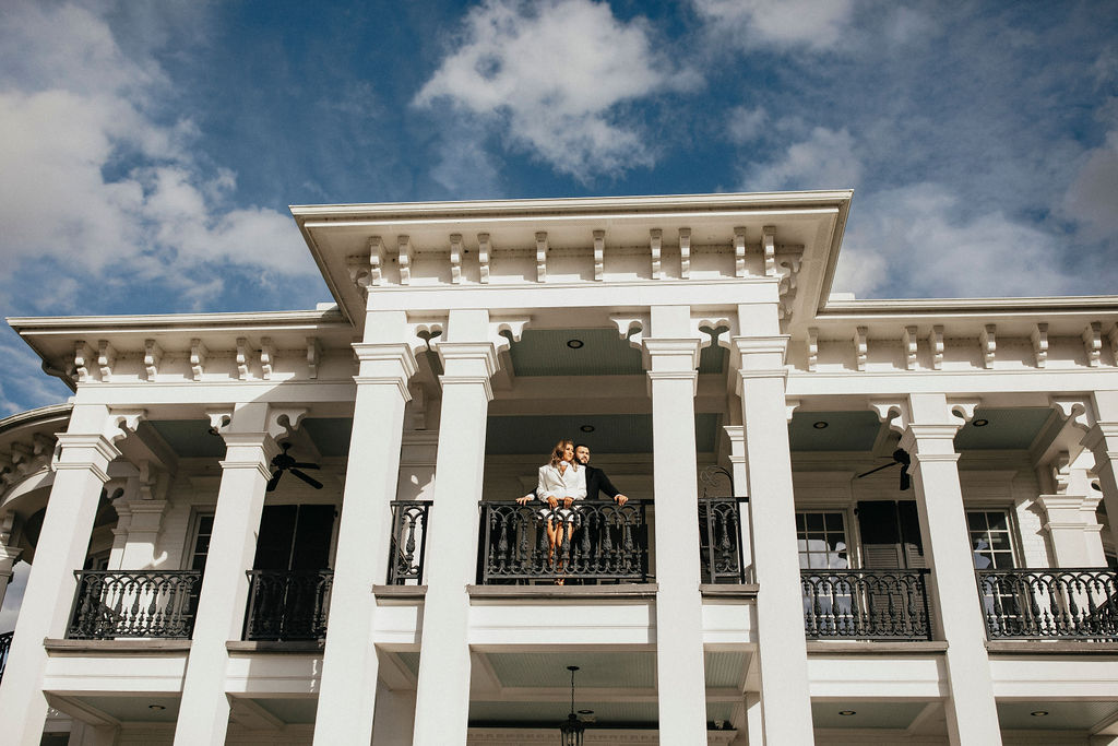 A couple poses for Houston engagement photos on the balcony at Sandlewood Manor