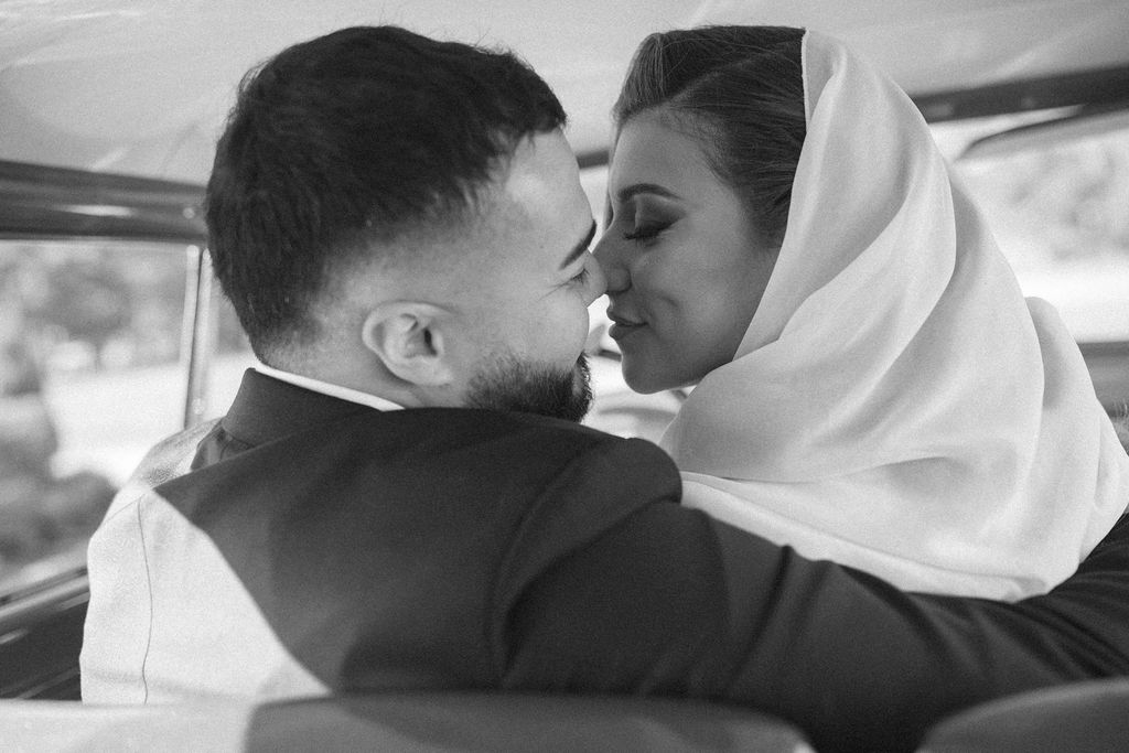 A b+w image depicts a couple's Houston engagement photos at Sandlewood Manor inside a vintage car