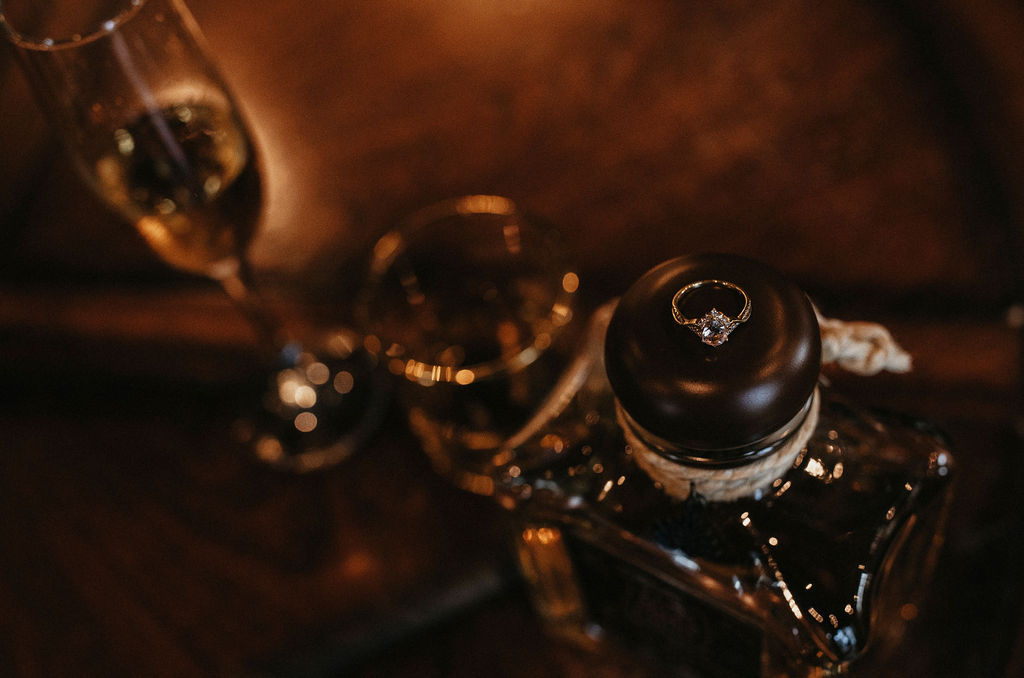Houston engagement photos showcase a diamond engagement ring atop a decanter at Sandlewood Manor
