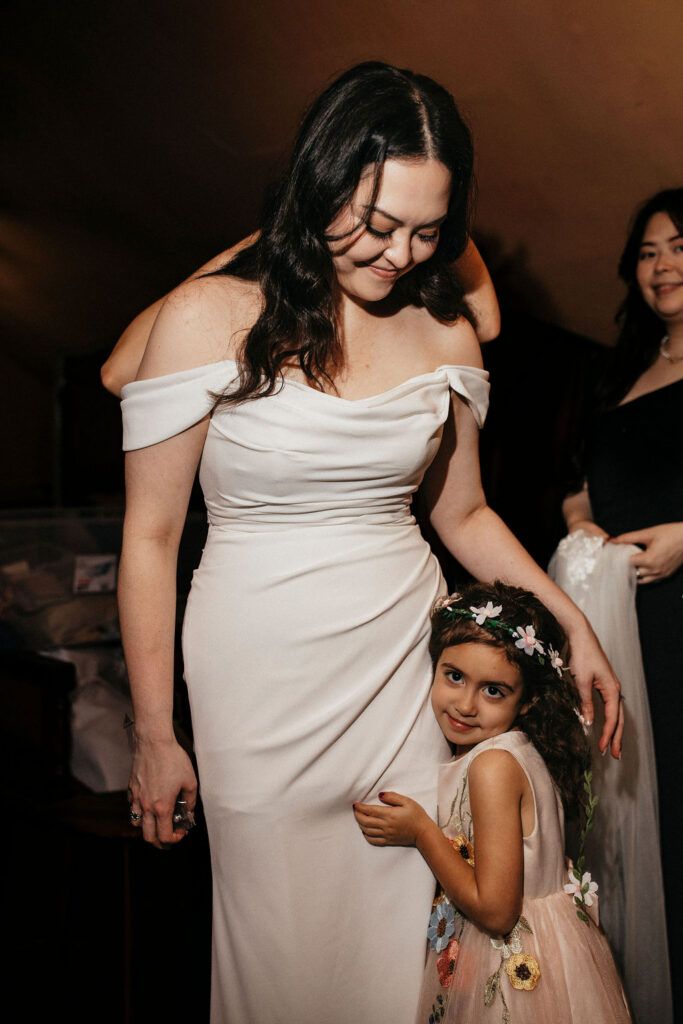 A flower girl hugs a Texas bride at her Avant Garden wedding in Houston TX. 