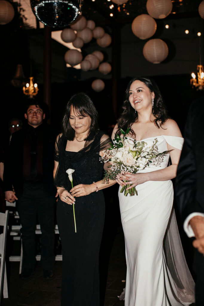 A bride walks down the aisle with her mother at her Avant Garden Houston wedding. 