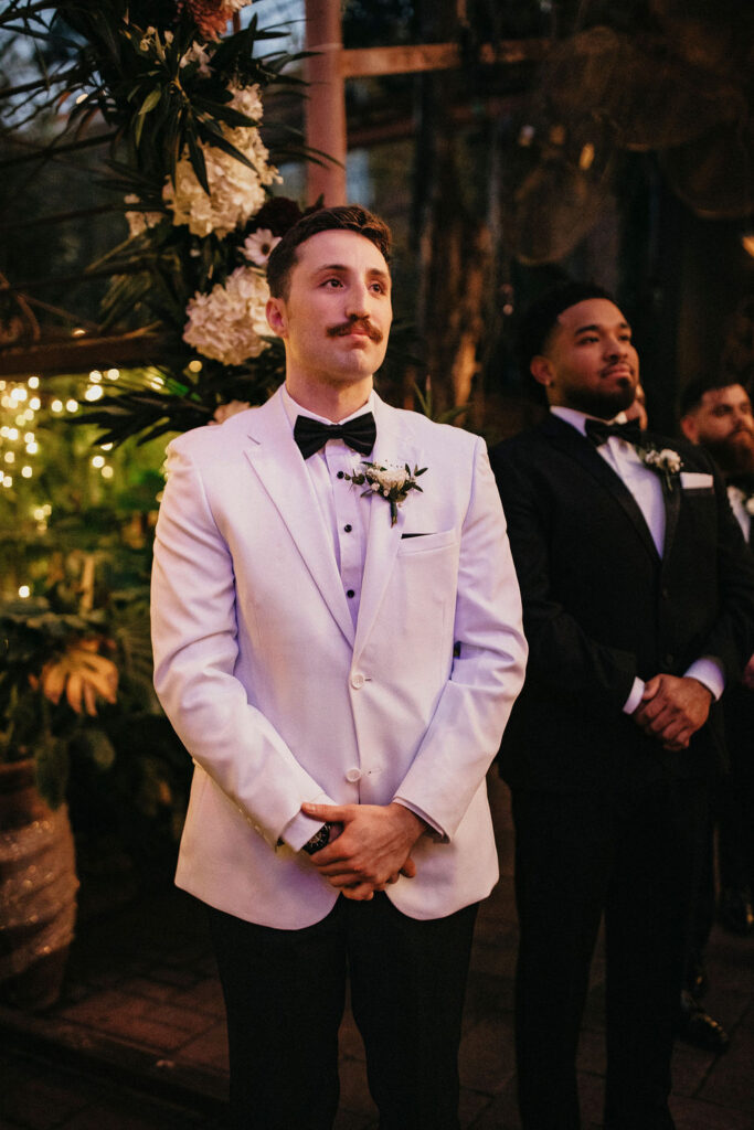 A groom watches as his bride walks toward him down the aisle at their Avant Garden wedding in Houston. 