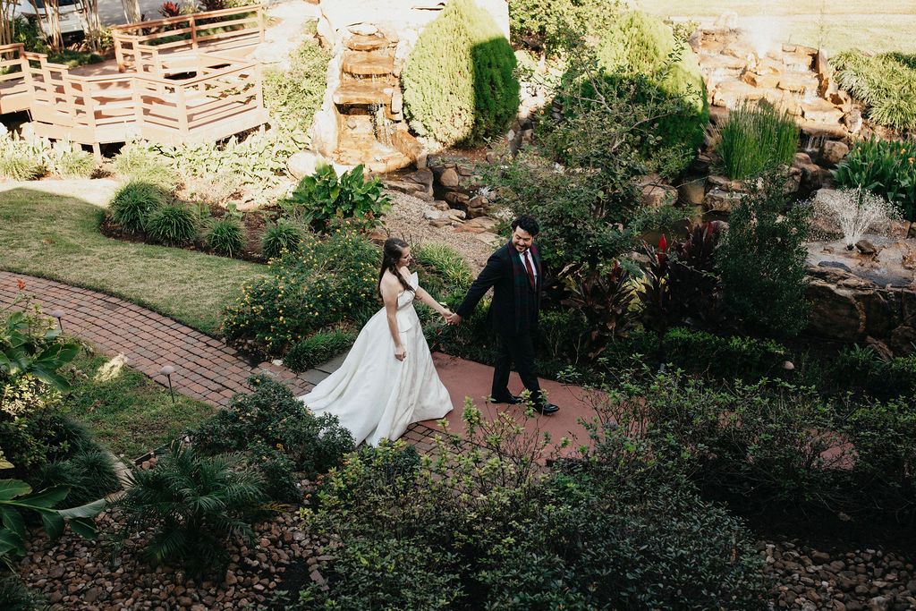Newlyweds walk along a brick path at Brenner's Bayou where they held their Houston elopement.