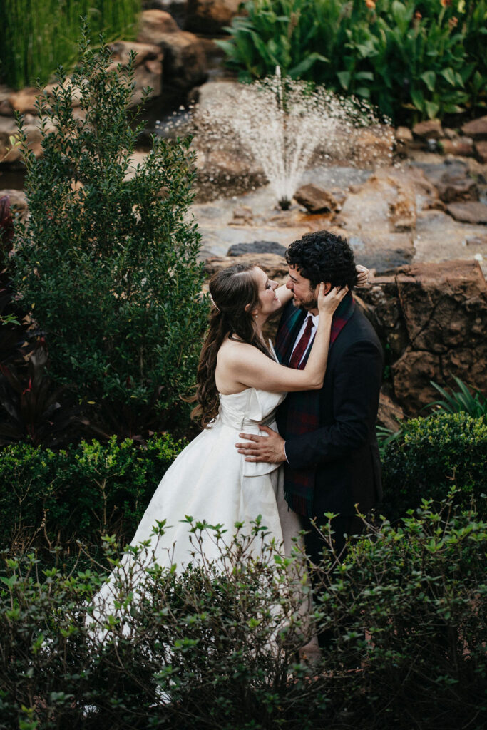 Newlyweds pose for a bridal portrait in front of a fountain at Brenner's on the Bayou. 