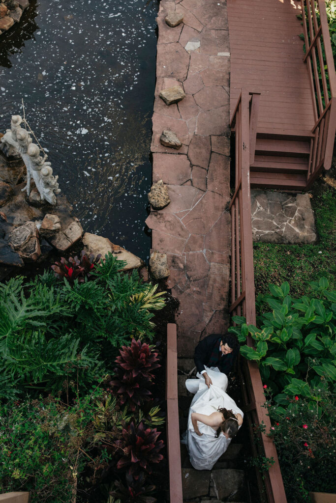 An aerial photo of a groom assisting his bride with the train of her dress at their Houston elopement. 