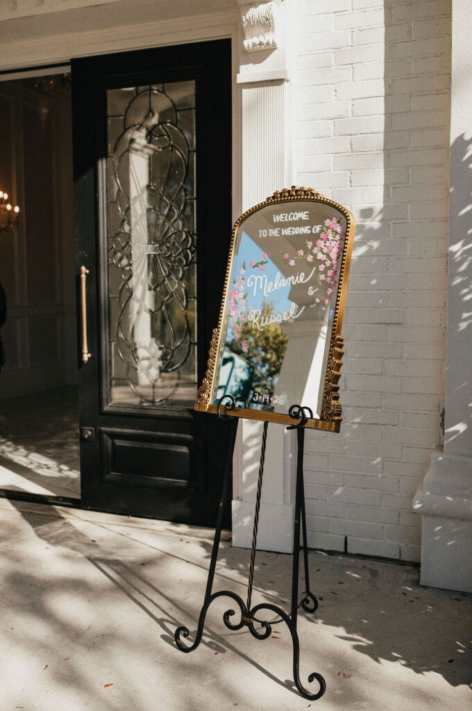 An antique mirror acts as a welcome sign for guests at a Sandlewood Manor wedding in Texas. 