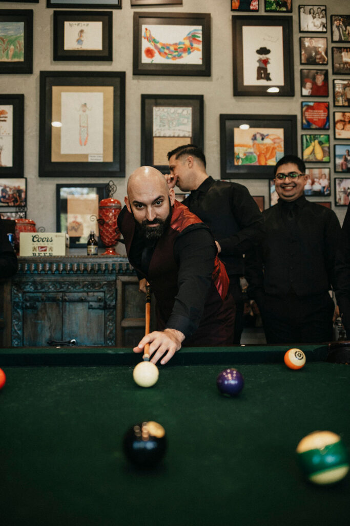 A groom plays a game of pool while he waits for his Texas ranch wedding ceremony at m3 ranch.